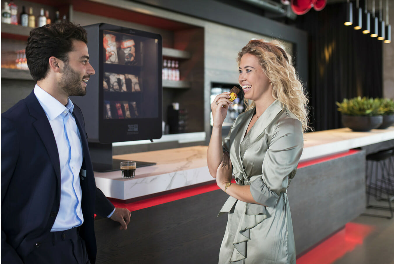 2 mensen praten aan de bar naast een smart vending machine van Junea