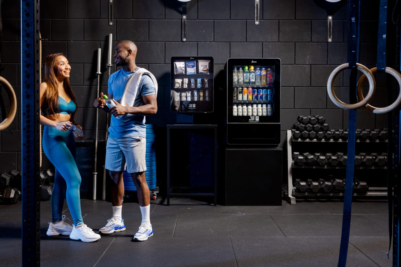 man en vrouw praten naast de junea vending machines in de sportschool - CrossFit